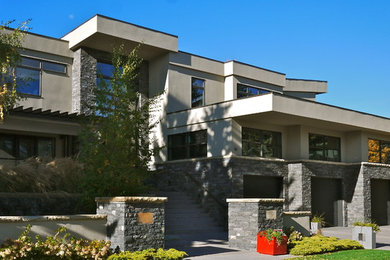 Inspiration for a large modern two-storey stucco beige exterior in Calgary with a flat roof.
