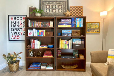 Imagen de sala de estar con biblioteca abierta escandinava con paredes beige y suelo laminado