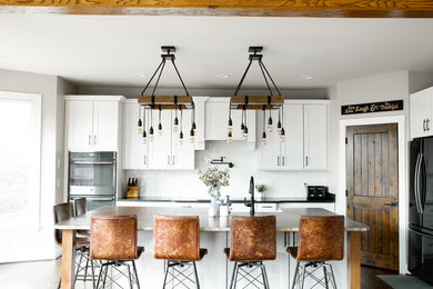 Eat-in kitchen - large cottage l-shaped medium tone wood floor and brown floor eat-in kitchen idea in Charlotte with a farmhouse sink, shaker cabinets, white cabinets, granite countertops, white backsplash, subway tile backsplash, stainless steel appliances, an island and brown countertops