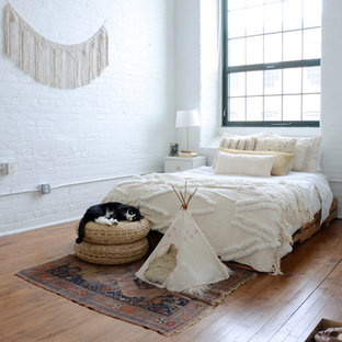 Aménagement d'une chambre éclectique avec un mur blanc, un sol en bois brun et un sol marron.
