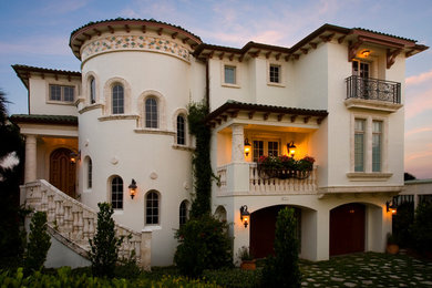 Photo of a mid-sized mediterranean three-storey stucco white house exterior in Tampa with a flat roof.