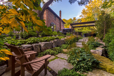 This is an example of a mid-sized rustic partial sun stone landscaping in Toronto.