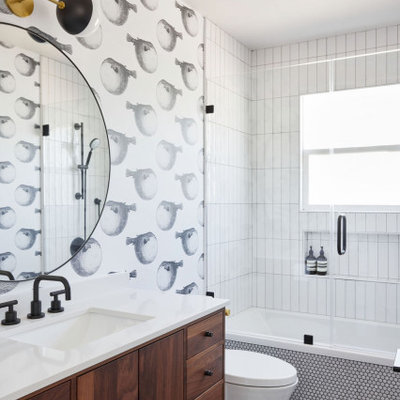 Example of a mid-sized mid-century modern kids' white tile and ceramic tile porcelain tile, gray floor, single-sink and wallpaper drop-in bathtub design in San Francisco with flat-panel cabinets, brown cabinets, a one-piece toilet, a drop-in sink, quartz countertops, a hinged shower door, white countertops and a freestanding vanity