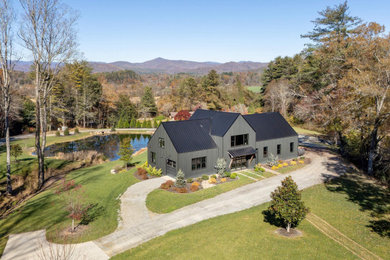 Example of a large farmhouse black metal exterior home design in Other with a metal roof and a black roof