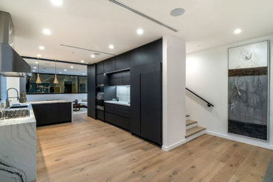 Example of a mid-sized l-shaped eat-in kitchen design in Dallas with flat-panel cabinets, black cabinets, marble countertops, white backsplash and white countertops