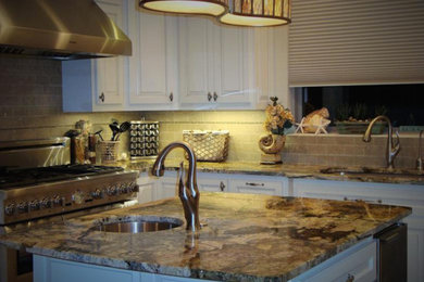 Example of a mid-sized l-shaped kitchen design in Austin with raised-panel cabinets, white cabinets, granite countertops, beige backsplash, stainless steel appliances and an island