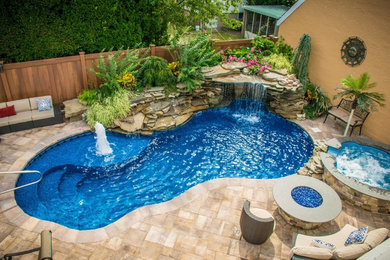 Design ideas for a large contemporary backyard custom-shaped lap pool in New York with a hot tub and natural stone pavers.