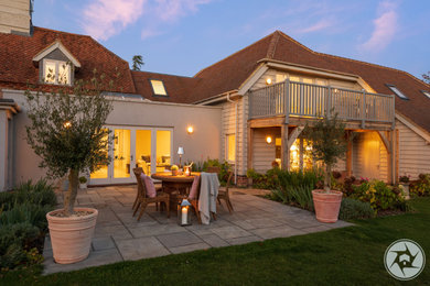 Photo of a large and beige contemporary two floor rear detached house in Oxfordshire with wood cladding, a tiled roof and a red roof.