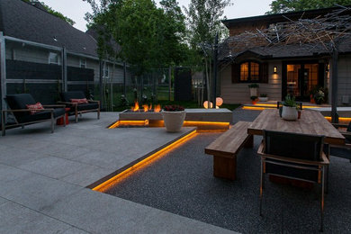 Photo of a large contemporary backyard patio in Kansas City with a fire feature, concrete pavers and a pergola.