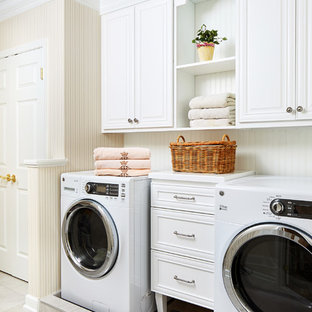 Diseño de cuarto de lavado clásico con armarios con paneles con relieve, puertas de armario blancas, paredes beige, lavadora y secadora juntas, suelo beige y encimeras blancas