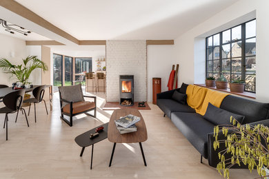 This is an example of a contemporary living room in Gloucestershire with white walls, light hardwood floors, a wood stove, a brick fireplace surround and beige floor.