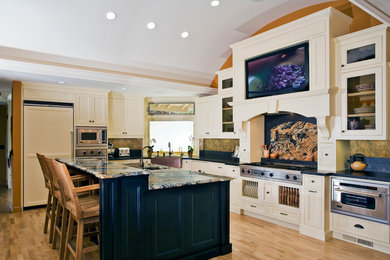 Example of a mid-sized island style l-shaped light wood floor kitchen design in San Francisco with a farmhouse sink, shaker cabinets, white cabinets, soapstone countertops, stone slab backsplash, stainless steel appliances and an island