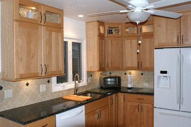 Mid-sized traditional l-shaped eat-in kitchen in Chicago with an undermount sink, shaker cabinets, light wood cabinets, granite benchtops, beige splashback, porcelain splashback, white appliances and ceramic floors.