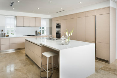 Contemporary l-shaped kitchen in Perth with an undermount sink, flat-panel cabinets, light wood cabinets, stainless steel appliances, with island, beige floor and white benchtop.