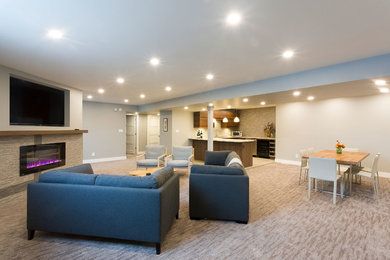 Inspiration for a large modern look-out carpeted and beige floor basement remodel in Other with beige walls and a stone fireplace