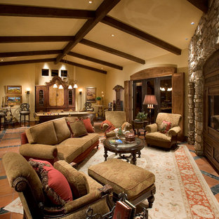 This is an example of an expansive mediterranean formal open plan living room in Phoenix with beige walls, brick flooring, a standard fireplace, a stone fireplace surround, a built-in media unit and red floors.