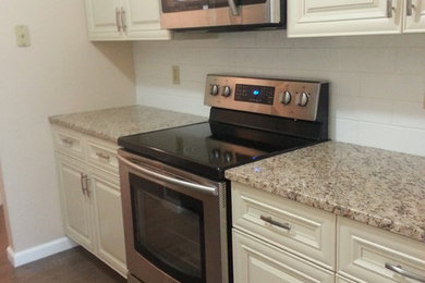 Example of a small classic single-wall dark wood floor enclosed kitchen design in New York with an undermount sink, raised-panel cabinets, white cabinets, granite countertops, white backsplash, subway tile backsplash and stainless steel appliances