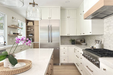 Mid-sized minimalist l-shaped light wood floor, brown floor and vaulted ceiling kitchen pantry photo in Los Angeles with a farmhouse sink, shaker cabinets, white cabinets, laminate countertops, white backsplash, ceramic backsplash, stainless steel appliances, an island and white countertops