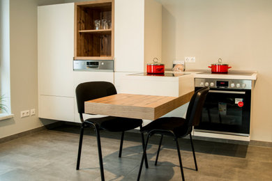 Einzeilige, Kleine Moderne Küche mit flächenbündigen Schrankfronten, weißen Schränken, Küchenrückwand in Weiß, Küchengeräten aus Edelstahl, Zementfliesen für Boden, Halbinsel, grauem Boden und weißer Arbeitsplatte in Sonstige