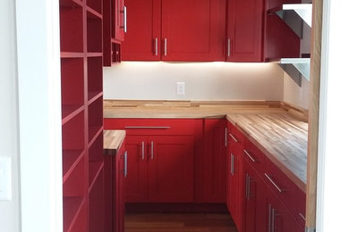 Eat-in kitchen - modern galley medium tone wood floor eat-in kitchen idea in Jacksonville with an undermount sink, flat-panel cabinets, red cabinets, wood countertops, stainless steel appliances and an island