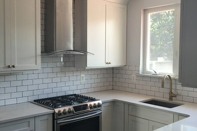 Inspiration for a mid-sized contemporary u-shaped separate kitchen in New York with an undermount sink, shaker cabinets, white cabinets, solid surface benchtops, white splashback, subway tile splashback, stainless steel appliances, slate floors, no island and black floor.