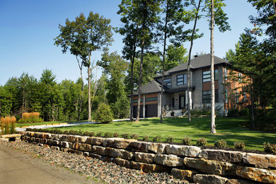Photo of a modern front yard full sun driveway for summer in Montreal with a retaining wall and natural stone pavers.
