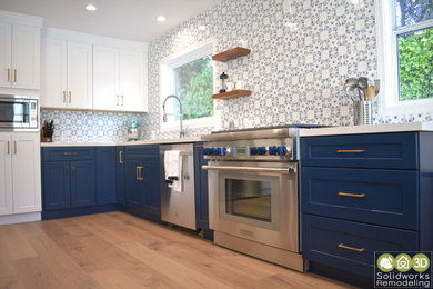 Large midcentury l-shaped eat-in kitchen in Los Angeles with a drop-in sink, shaker cabinets, quartzite benchtops, blue splashback, porcelain splashback, stainless steel appliances, painted wood floors, with island, beige floor and white benchtop.