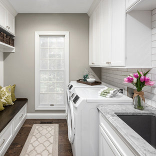 This is an example of a medium sized traditional galley utility room in St Louis with a submerged sink, flat-panel cabinets, white cabinets, quartz worktops, grey walls, medium hardwood flooring, a side by side washer and dryer, brown floors and grey worktops.
