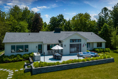 Diseño de fachada de casa blanca y gris de tamaño medio de una planta con tejado de teja de madera, revestimiento de aglomerado de cemento, tejado a dos aguas y panel y listón