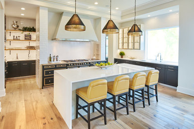 Example of a large transitional u-shaped light wood floor eat-in kitchen design in Minneapolis with a double-bowl sink, flat-panel cabinets, black cabinets, quartz countertops, white backsplash, ceramic backsplash, black appliances and an island