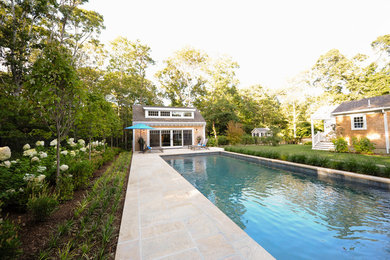 This is an example of a beach style backyard rectangular pool in Boston with a pool house and natural stone pavers.