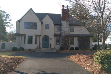Inspiration for a large transitional beige two-story stucco exterior home remodel in Other with a clipped gable roof