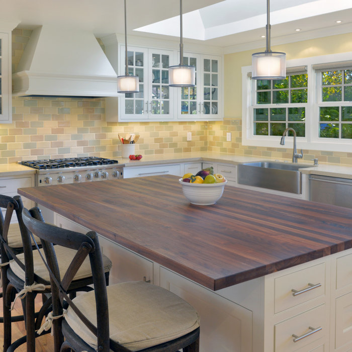 Mid-sized elegant light wood floor open concept kitchen photo in San Francisco with a farmhouse sink, white cabinets, wood countertops, yellow backsplash and stainless steel appliances