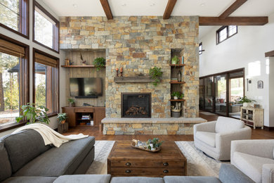 Landhaus Wohnzimmer mit braunem Holzboden, Kaminumrandung aus Stein und freigelegten Dachbalken in Denver