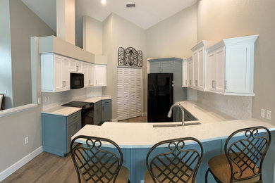 Large transitional galley eat-in kitchen in Tampa with an undermount sink, shaker cabinets, white cabinets, quartz benchtops, white splashback, porcelain splashback, black appliances, laminate floors, grey floor, white benchtop and vaulted.