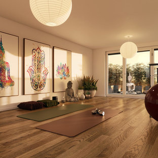 Esempio di uno studio yoga etnico di medie dimensioni con pareti bianche, pavimento in legno massello medio e pavimento marrone