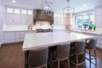 Medium tone wood floor and brown floor eat-in kitchen photo in Chicago with a farmhouse sink, beaded inset cabinets, white cabinets, white backsplash, stainless steel appliances, an island and white countertops