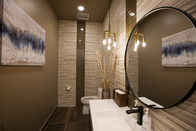 Inspiration for a mid-sized contemporary brown tile porcelain tile and brown floor powder room remodel in Denver with flat-panel cabinets, medium tone wood cabinets, a one-piece toilet, brown walls, an integrated sink, solid surface countertops, white countertops and a floating vanity