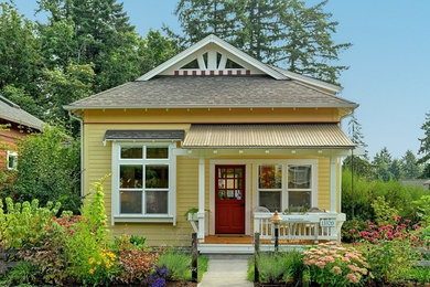 Example of a small arts and crafts yellow two-story concrete fiberboard house exterior design in Other with a hip roof and a shingle roof