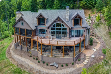 Huge mountain style multicolored three-story stucco exterior home photo in Other with a shingle roof