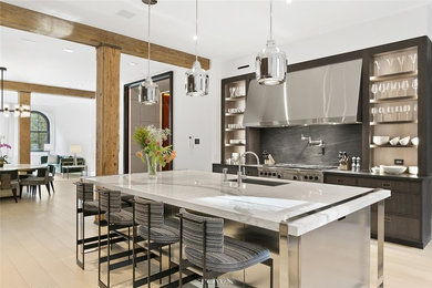 Large trendy single-wall light wood floor and beige floor kitchen photo in New York with an undermount sink, flat-panel cabinets, dark wood cabinets, quartzite countertops, black backsplash, stainless steel appliances, an island and white countertops