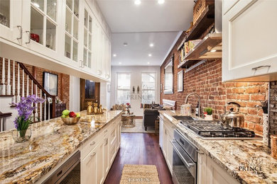 Eat-in kitchen - large industrial galley medium tone wood floor and brown floor eat-in kitchen idea in New York with an undermount sink, recessed-panel cabinets, granite countertops, red backsplash, brick backsplash, stainless steel appliances, an island and white cabinets