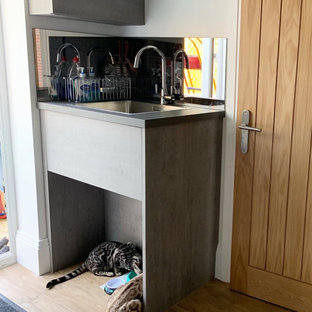 Idéer för att renovera en liten tvättstuga, med en enkel diskho, släta luckor och spegel som stänkskydd