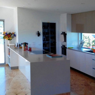 Design ideas for a mid-sized contemporary u-shaped kitchen pantry with an undermount sink, white cabinets, quartz benchtops, glass sheet splashback, white appliances, plywood floors, with island and flat-panel cabinets.