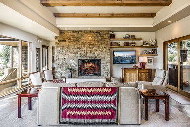 Design ideas for a small country open concept family room in Other with beige walls, travertine floors, a standard fireplace, a stone fireplace surround, a wall-mounted tv and grey floor.