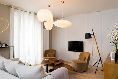 This is an example of a contemporary formal enclosed living room in Paris with beige walls, medium hardwood floors, a wall-mounted tv and yellow floor.