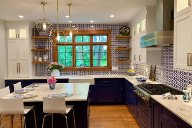 Inspiration for a mid-sized eclectic u-shaped medium tone wood floor and brown floor enclosed kitchen remodel in Milwaukee with a farmhouse sink, flat-panel cabinets, white cabinets, marble countertops, blue backsplash, porcelain backsplash, paneled appliances, an island and white countertops