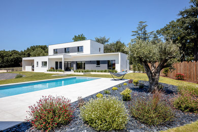 Réalisation d'un grand piscine avec aménagement paysager arrière design rectangle avec des pavés en béton.