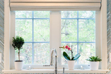 Photo of a medium sized coastal l-shaped kitchen/diner in Boston with a submerged sink, shaker cabinets, white cabinets, engineered stone countertops, blue splashback, glass tiled splashback, stainless steel appliances, medium hardwood flooring, an island, brown floors, white worktops and a vaulted ceiling.