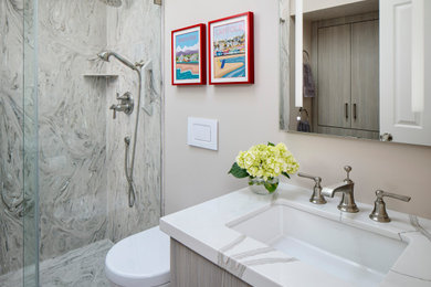 Photo of a mid-sized contemporary bathroom in San Francisco with flat-panel cabinets, grey cabinets, a one-piece toilet, gray tile, beige walls, ceramic floors, an undermount sink, engineered quartz benchtops, grey floor, a sliding shower screen and white benchtops.